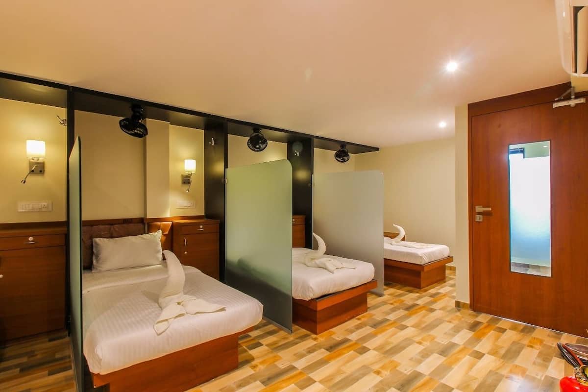 Habitación de hotel con dos camas, un espejo y una puerta de madera.