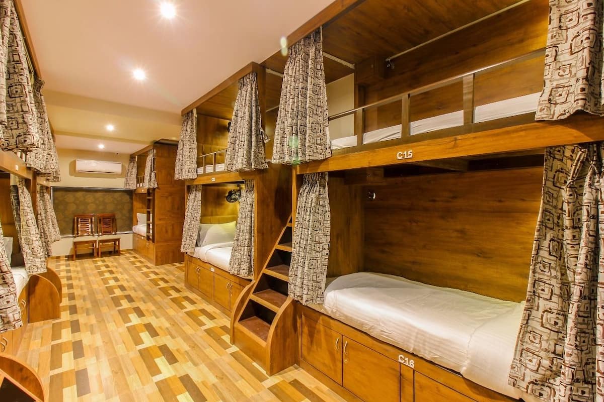 Una habitación con literas, piso de madera y cortinas estampadas.