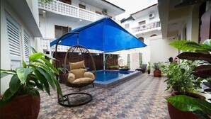 Un patio con una hamaca colgante, una piscina pequeña y plantas en macetas.
