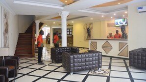 Un vestíbulo con piso a cuadros, una escalera y una zona de recepción con televisor.