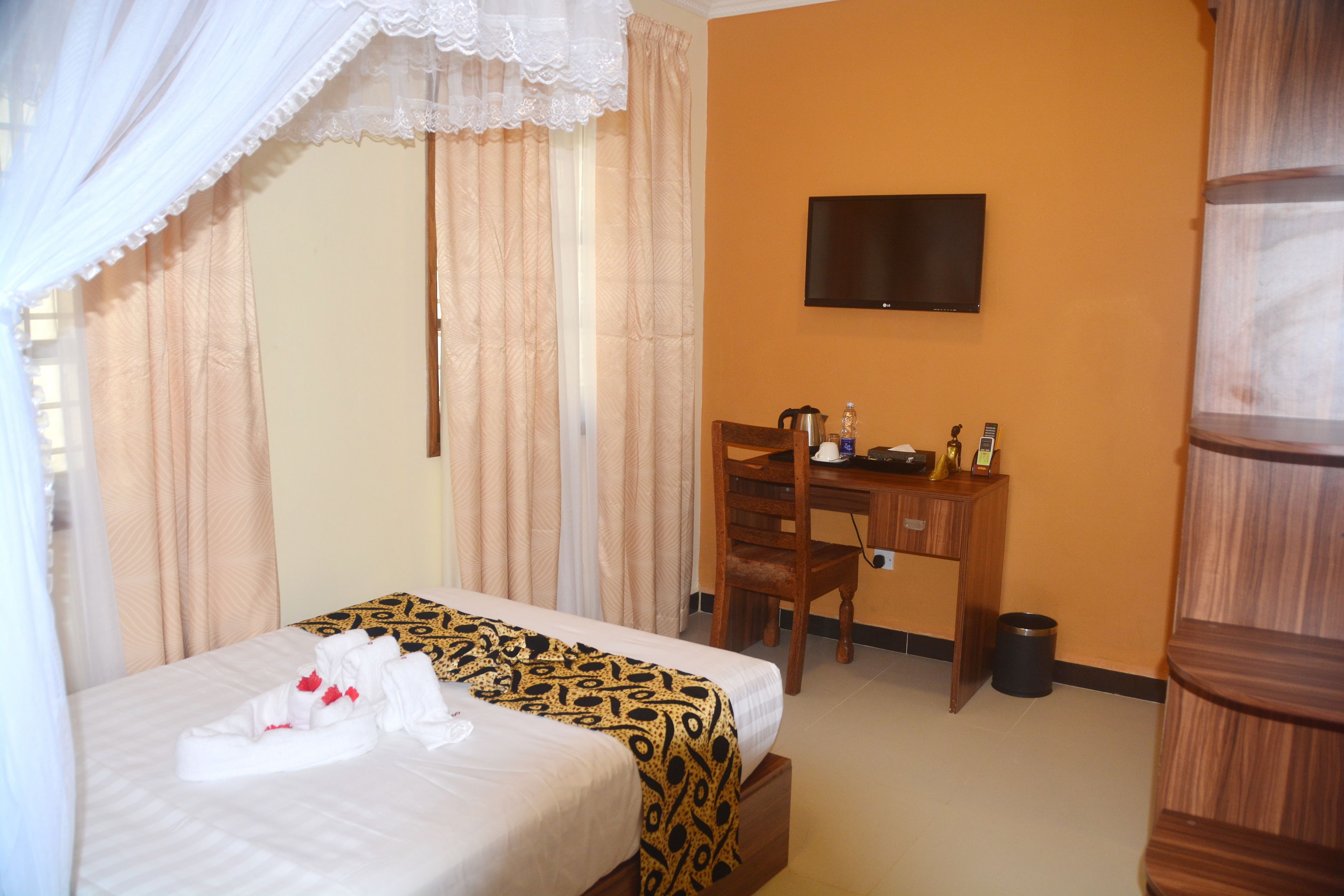Una habitación de hotel con una cama, un escritorio, una silla, un televisor y un bote de basura.