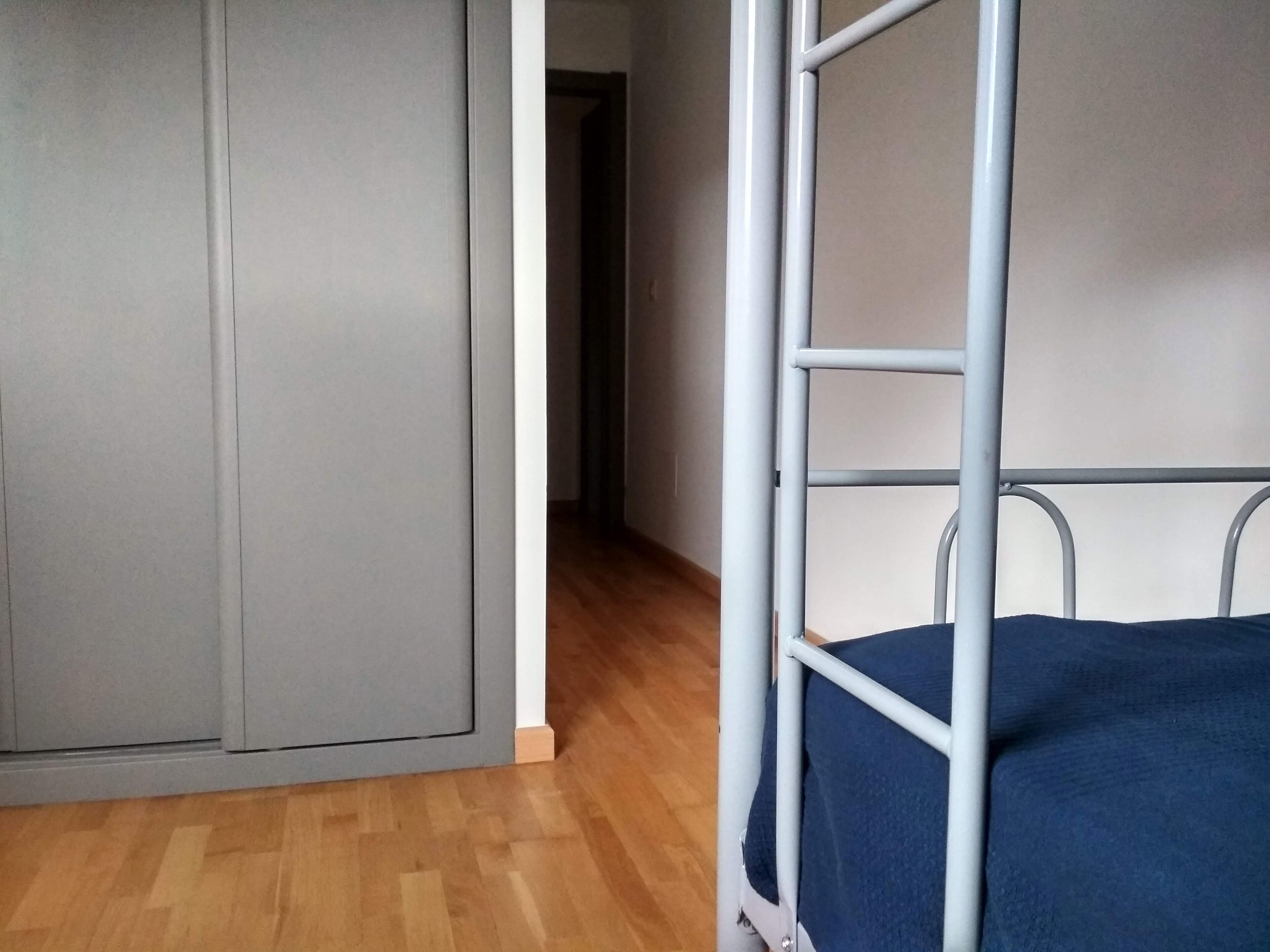 Una habitación con literas, un armario y suelo de madera.