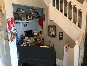 Une pièce encombrée avec un bureau, des étagères et un escalier.