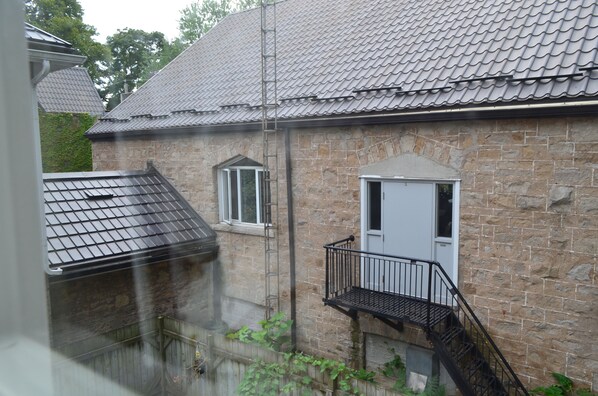 A stone building with a metal roof, a door, and a small balcony.