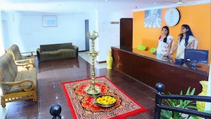 A hotel lobby with a reception desk, a sofa, a decorative lamp, and a patterned rug. - Oceanbay Ayurvedic Beach Resort (Neyyattinkara)