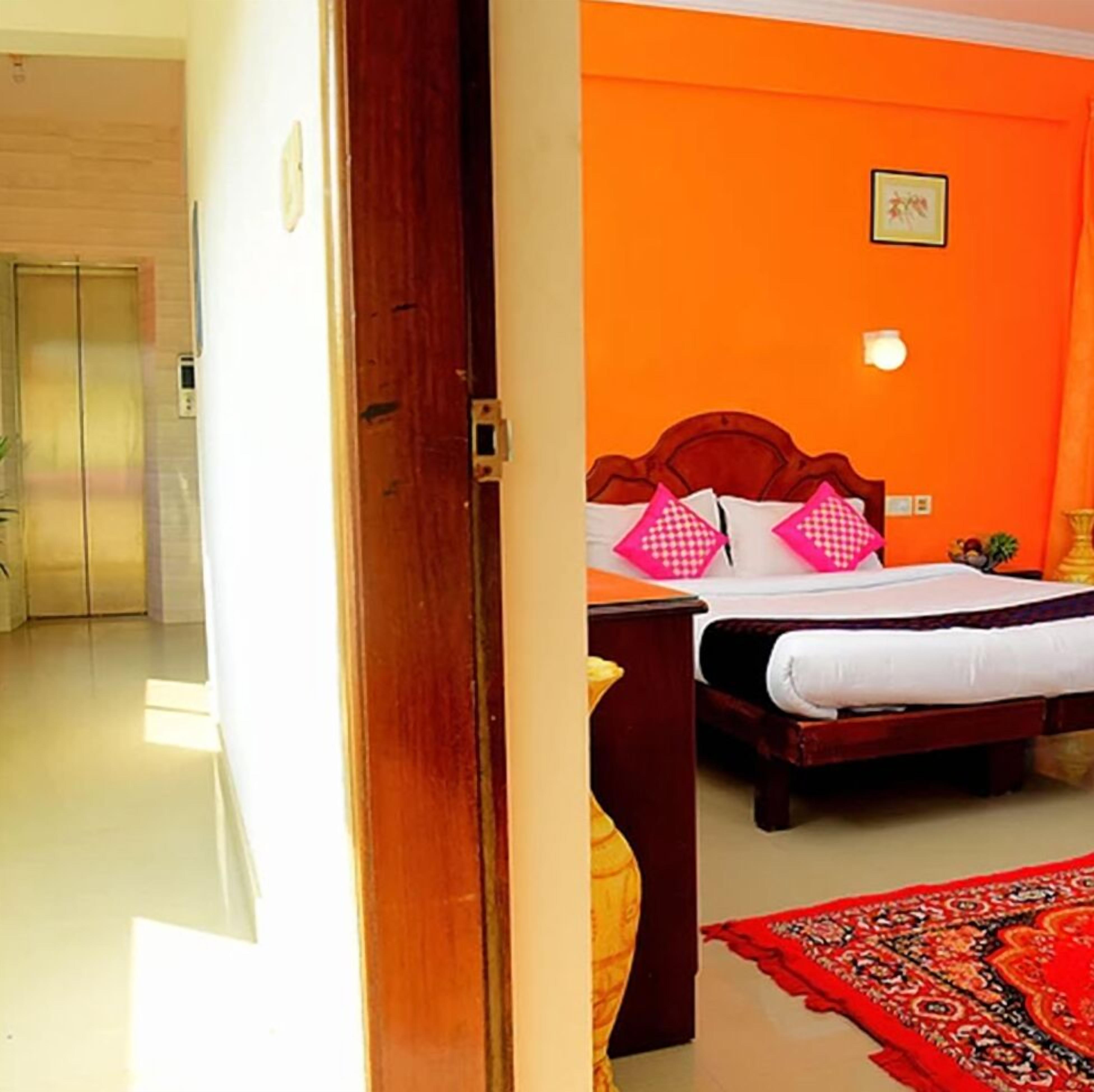A hotel room with a bed, a nightstand, and a red patterned rug.