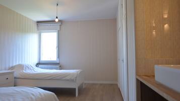 A bedroom with two beds, a window, and a radiator.