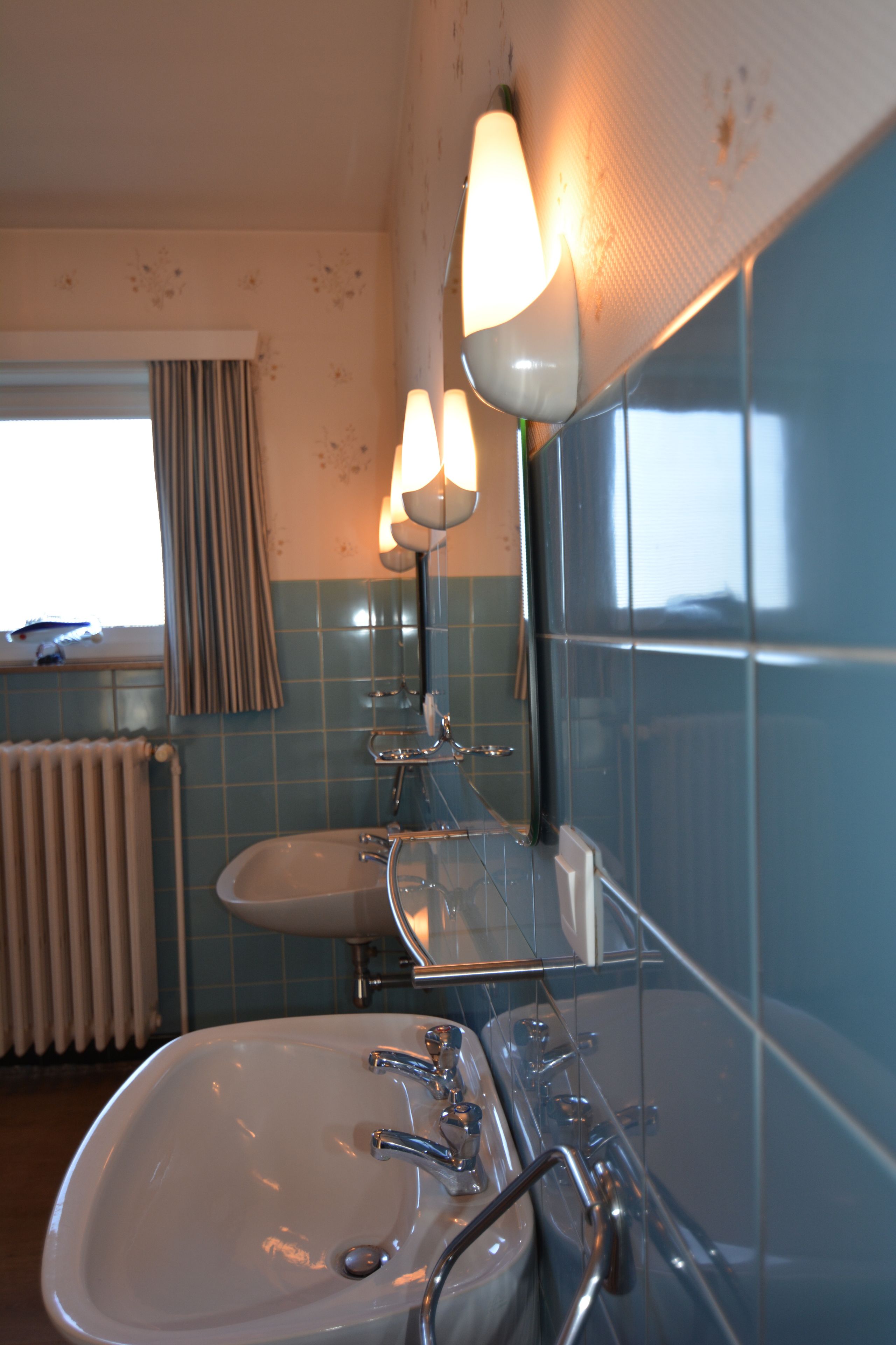 A bathroom with a sink, mirror, and two wall-mounted lights.