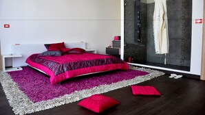 Un dormitorio moderno con una cama grande, un vestidor y una ducha con mampara de vidrio.