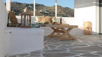 A terrace with a wooden table, wicker basket, and a view of mountains.