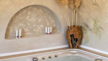 Un jacuzzi de diseño rústico, un jarrón decorativo con plumas de pampa y una pared con estampado floral.