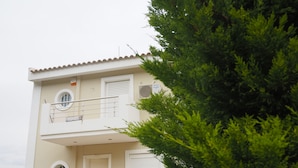 Un bâtiment à deux étages doté d’un balcon, d’une fenêtre avec un volet et d’une porte.