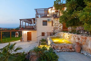 A two-story building with a stone facade, a balcony, and a small outdoor water feature. - Villa Laskari With Sea View (Nea Propontida)