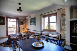 Una habitación acogedora con una cama, una mesa con una copa de vino y un muro de piedra.