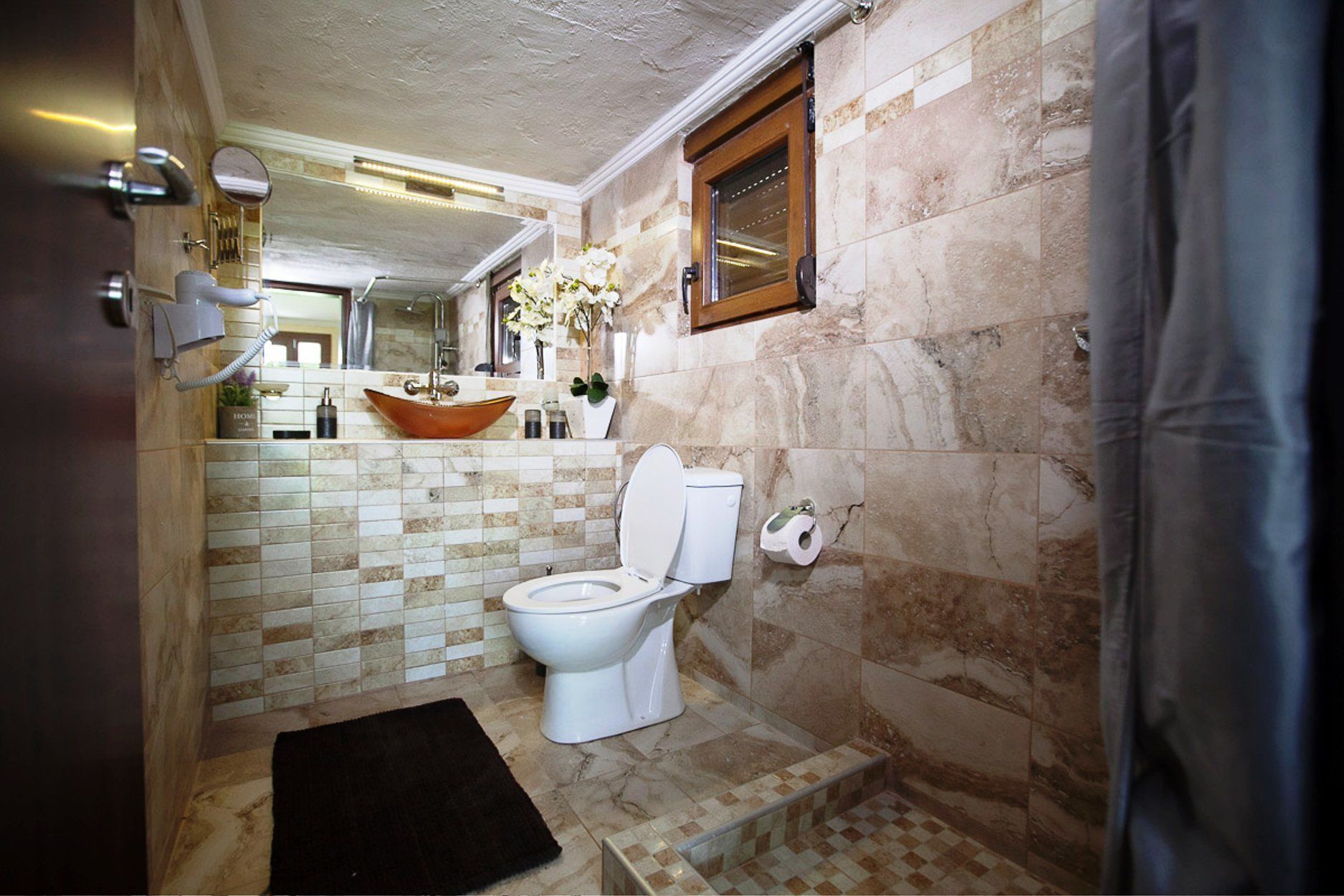 Une salle de bain avec des toilettes blanches, un lavabo en bois et un miroir au-dessus du lavabo.