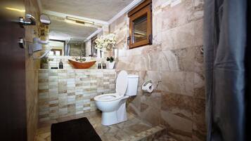 Une salle de bain avec des toilettes blanches, un lavabo en bois et un miroir au-dessus du lavabo.