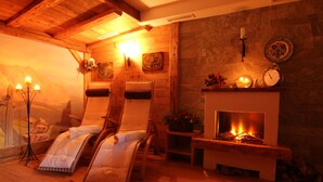 Une pièce chaleureuse avec une cheminée, des murs en bois et deux fauteuils inclinables.