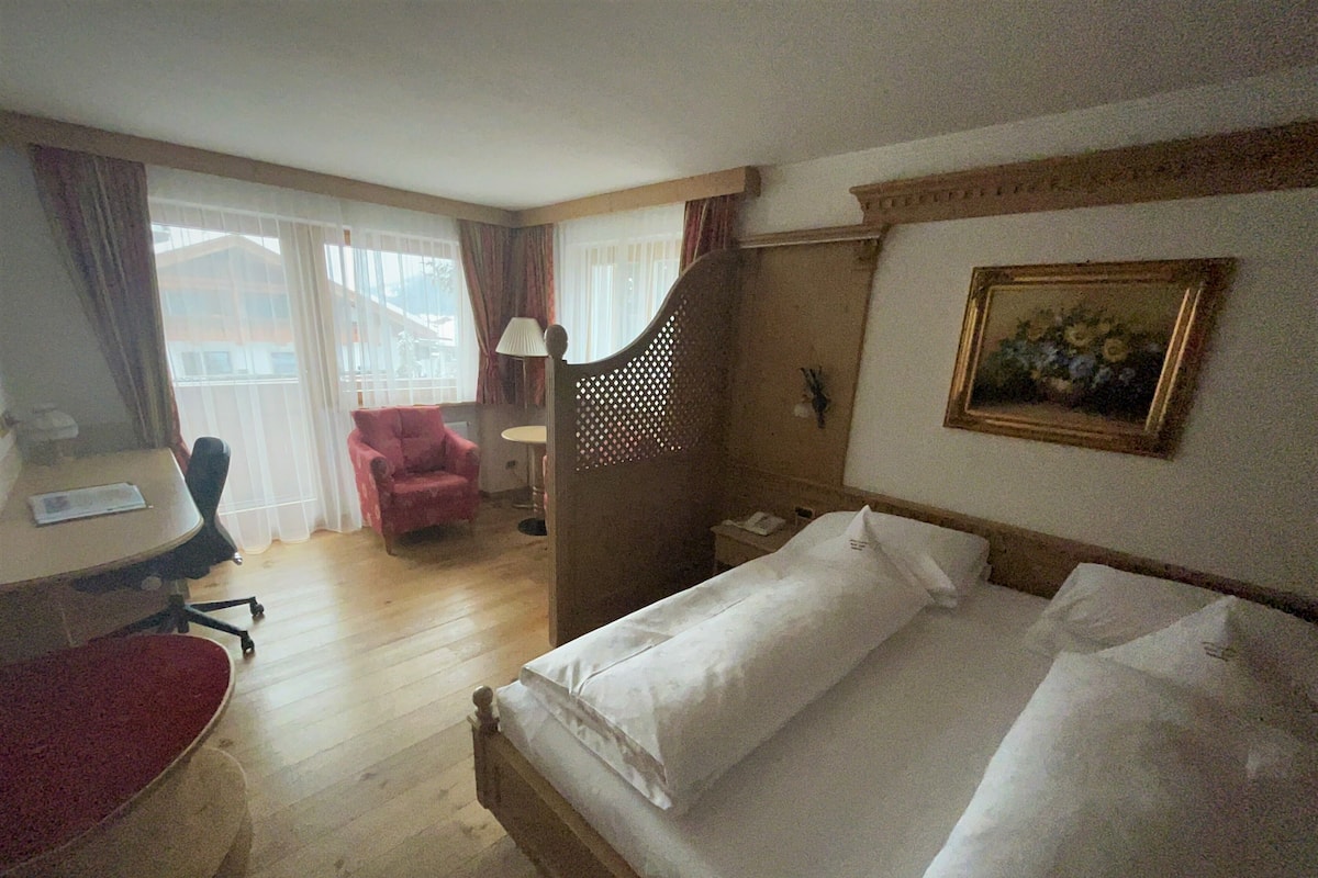 Une chambre d’hôtel avec un lit, un bureau, une chaise, une lampe et un tableau au mur.