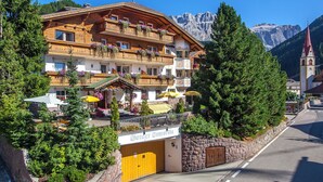 Un hôtel à plusieurs étages, doté de balcons, d’un mur en pierre et surplombant un paysage montagneux.