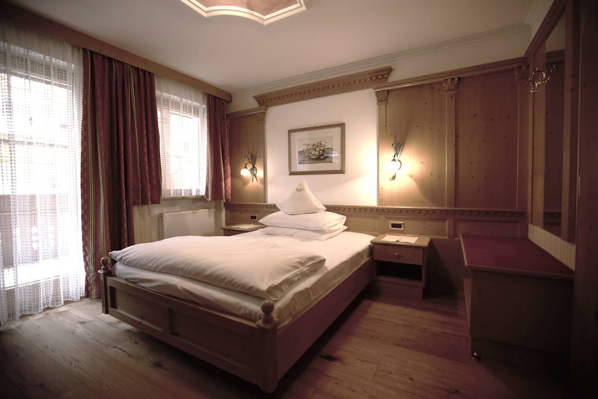 Une chambre à coucher avec un lit en bois, une table de chevet, un bureau et un miroir.
