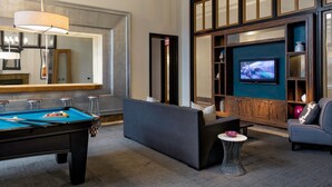 Un espace de détente moderne comprenant une table de billard, des canapés, un téléviseur et un coin bar.