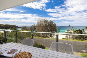 A balcony with a view of the ocean and a table with magazines. - Beach House - footsteps from the sand (Mollymook Beach)