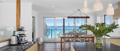 Una cocina moderna con vista al mar, que incluye una cafetera, un lavamanos y un comedor con mesa y sillas.