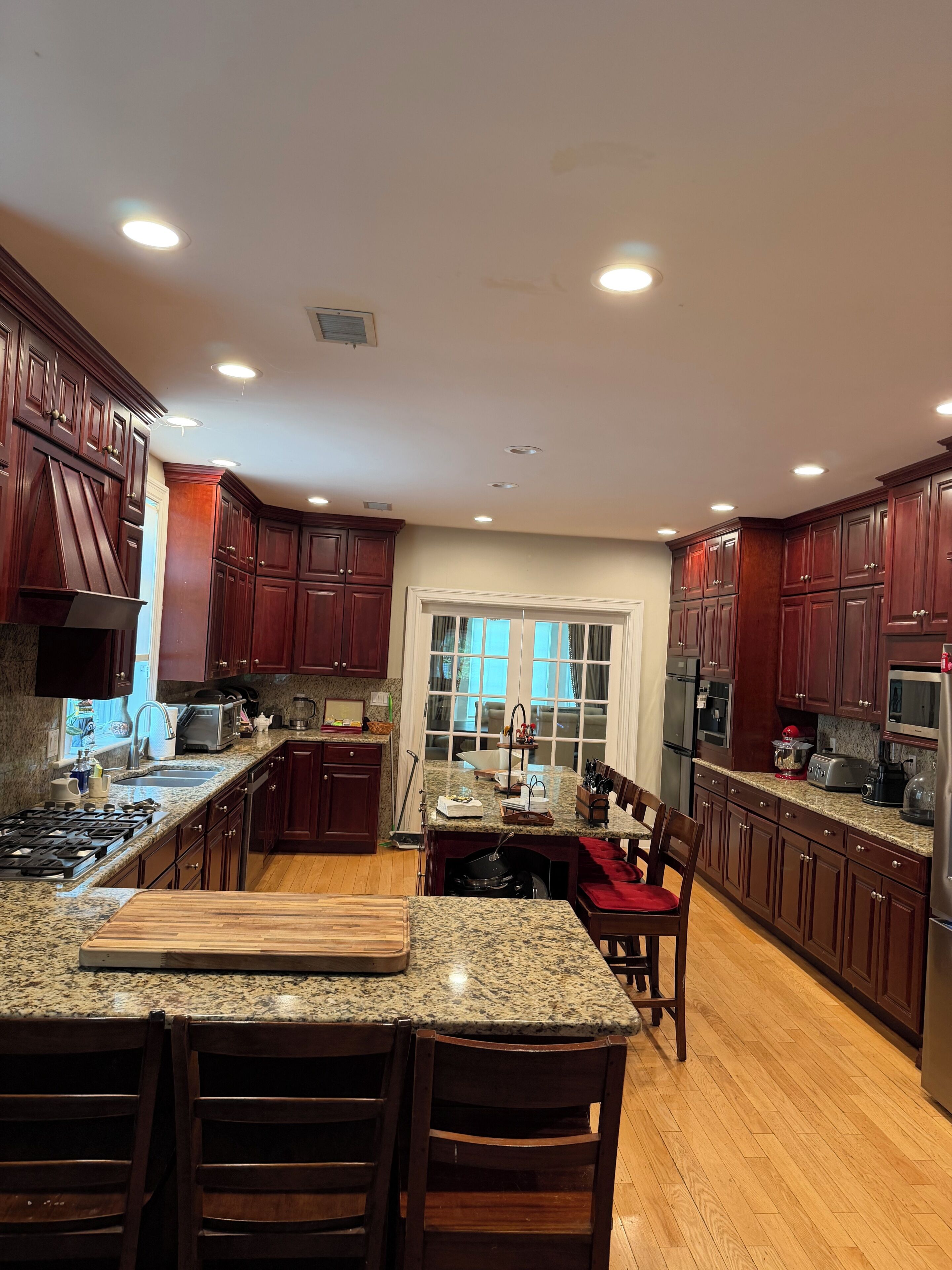 A kitchen with dark wood cabinets, granite countertops, stainless steel appliances, and a central island with seating.
