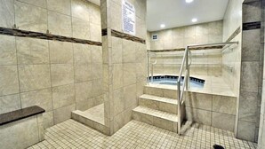 A shower area with tiled walls, a glass-enclosed shower, and a sign with rules. - El Matador 424 by Alicia Hollis Rentals FREE TICKETS! $300/Day (Fort Walton Beach)
