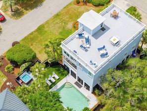 A modern two-story building with a rooftop deck, a swimming pool, and a hot tub.