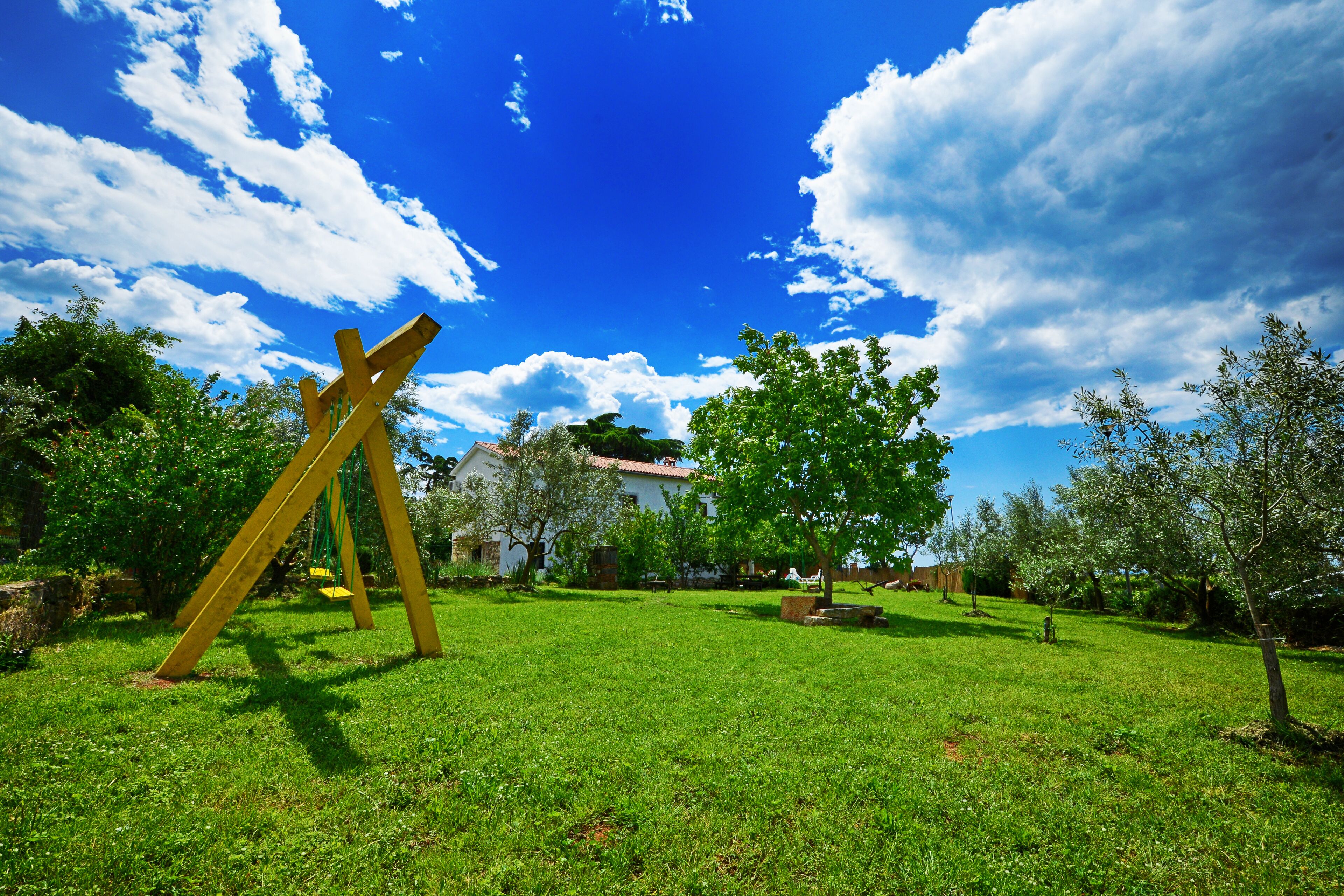 A grassy park with a swing set and a white building in the background.