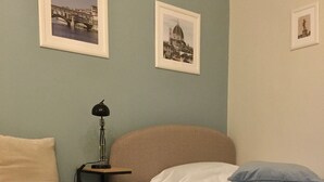 A hotel room with two beds, each with a blue and white duvet, a lamp on a bedside table, and framed pictures on the wall. - Independent studio near Santa Maria Novella Train Station (Firenze)