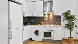 A modern kitchen with white cabinets, a built-in oven, a washing machine, and a plant. - Gran Vía II- Lovely apartment in the city center of Madrid (Madrid)