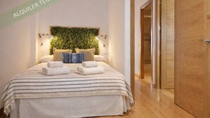 A bedroom with a bed, pillows, a headboard with greenery, and a wooden door. - Gran Vía II- Lovely apartment in the city center of Madrid (Madrid)