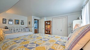 Quarto com uma cama grande, cômoda, penteadeira e uma porta que dá para outro espaço.