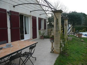 A patio with a table and chairs, a stone pillar, and potted plants.
