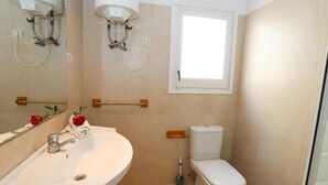 A bathroom with a white sink, a toilet, a showerhead, and a window. - 161 - COSTA AZUL LUXE..Spacious and central apartment with wonderful views (SALOU)