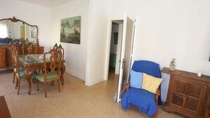 A living room with a dining area, a blue armchair, and a wooden cabinet. - 161 - COSTA AZUL LUXE..Spacious and central apartment with wonderful views (SALOU)