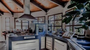 A kitchen with wooden beams, a central island with a sink, and large windows.