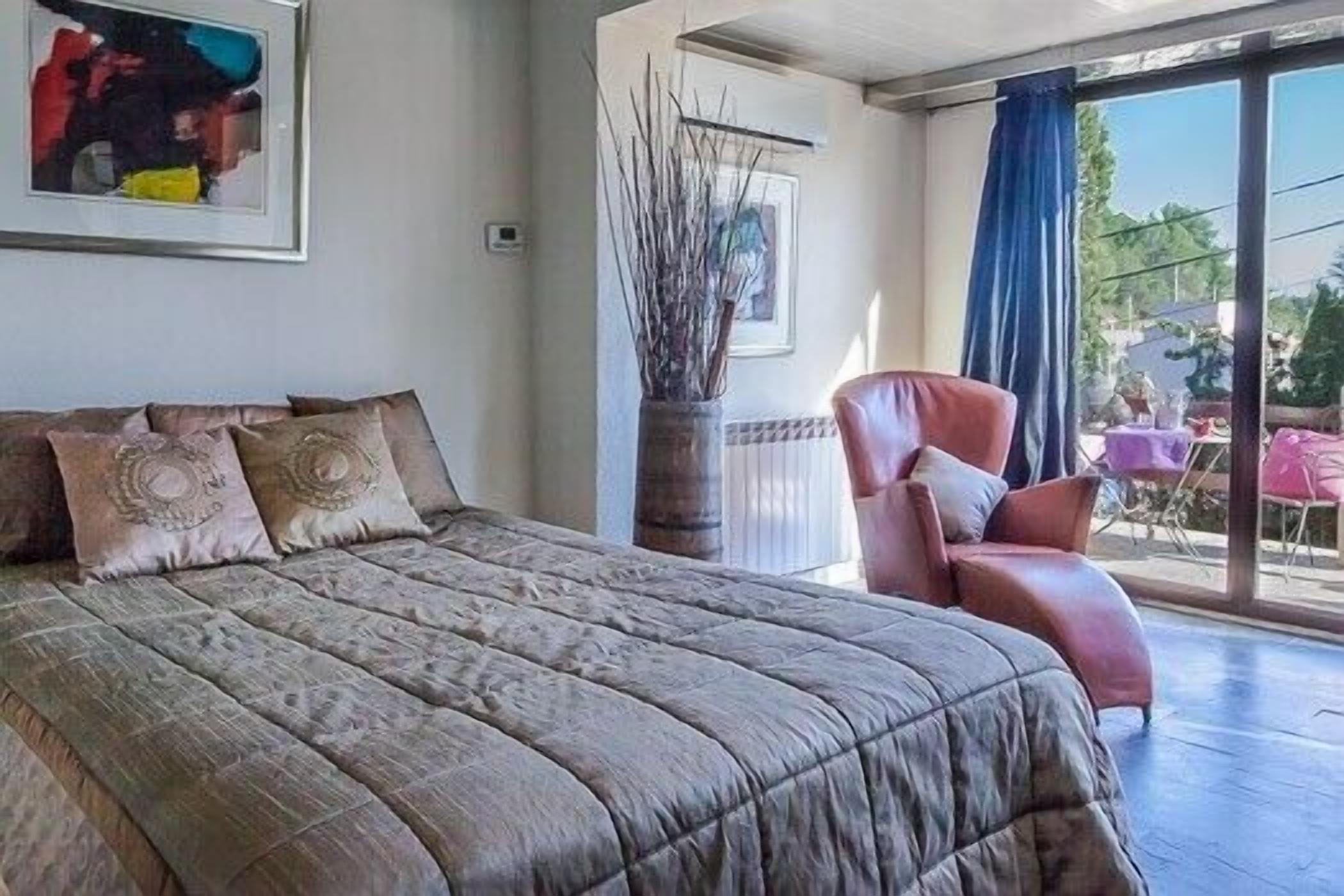 Un dormitorio con una cama grande, una silla y vistas al exterior.