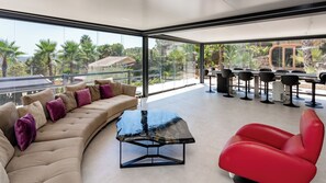 Un espace de vie moderne avec un canapé aux lignes courbes, une table basse en verre et un fauteuil rouge.