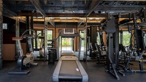 A gym with a treadmill, weight machines, and dumbbells.