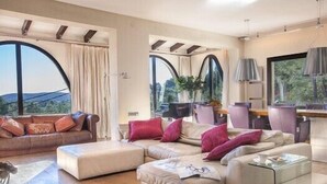 A modern living room with a sectional sofa, a glass coffee table, and a dining area with a table and chairs.