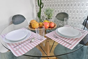 Une table à manger avec deux assiettes, un verre et un panier de fruits.