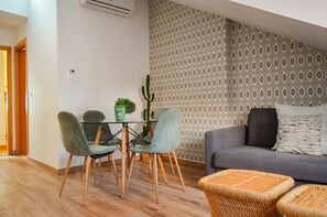 Un salon moderne avec un canapé gris, deux fauteuils, une petite table et un cactus.