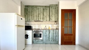 A compact kitchen with a refrigerator, washing machine, and oven.