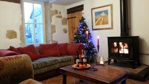 A cozy living room with a fireplace, a Christmas tree, and a sofa. - Beautiful Stone Farmhouse With Heated Pool And Views Across Rolling Countryside (Gondrin)