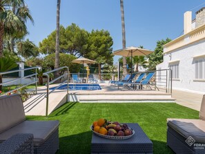 A pool area with lounge chairs, a fruit bowl, and a staircase leading to a pool. - Villa Comes - Beautiful villa with private pool 50 metres from the beach (Port d'Alcúdia)