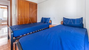 A room with two beds, a wooden wardrobe, and a white wall. - 131-POMPEYO II. Apartment located in Cambrils only 300m from the beach (Cambrils)