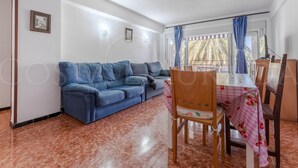 A living room with a sofa, a dining table with chairs, and a balcony with curtains. - 131-POMPEYO II. Apartment located in Cambrils only 300m from the beach (Cambrils)